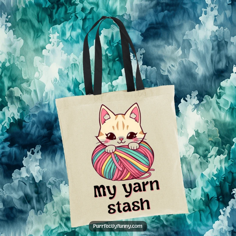 Funny tote bag picturing a cat with a mischievous grin peeking from behind a giant ball of colorful yarn.